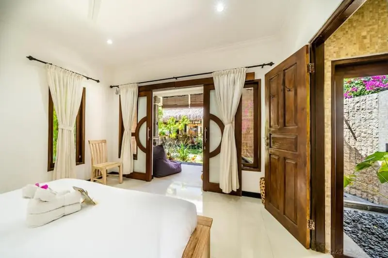Une chambre lumineuse avec un lit recouvert d'un drap blanc et un accès à une terrasse.