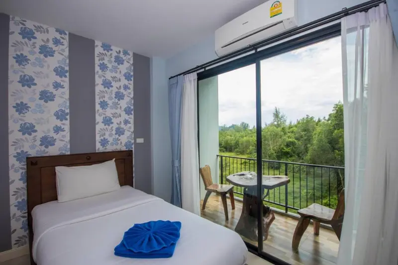 Une chambre lumineuse s'ouvre sur une terrasse avec vue sur la végétation.