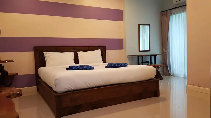 Une chambre avec un grand lit recouvert d'une courtepointe blanche et de deux serviettes bleues.