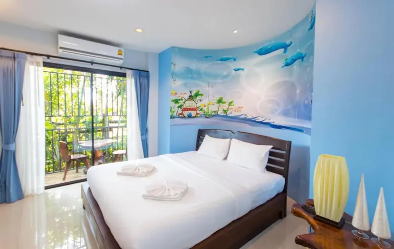 Une chambre lumineuse avec un grand lit et un balcon donnant sur la végétation.