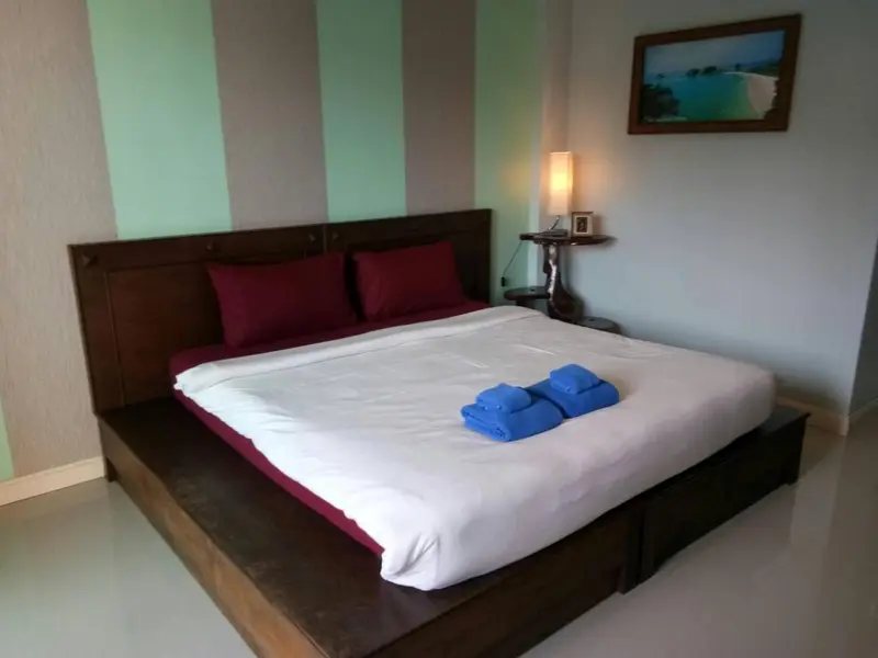 Une chambre avec un grand lit recouvert d'une courtepointe blanche et de coussins bordeaux.