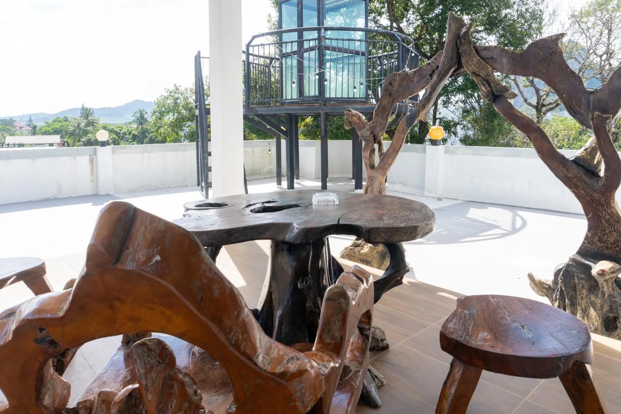 Terrasse aménagée avec mobilier en bois sculpté et vue sur la mer.