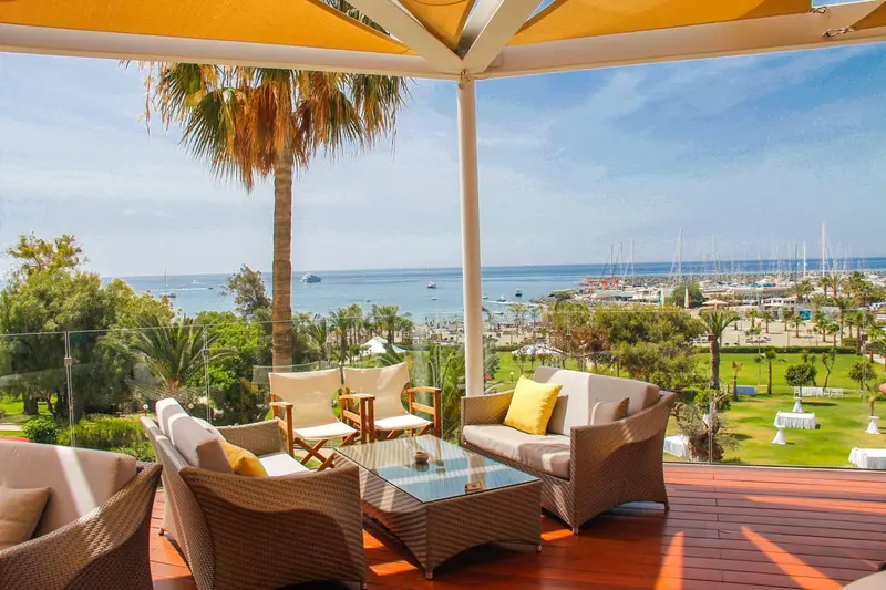 Salon d'extérieur avec canapés et vue sur la mer et un port de plaisance.