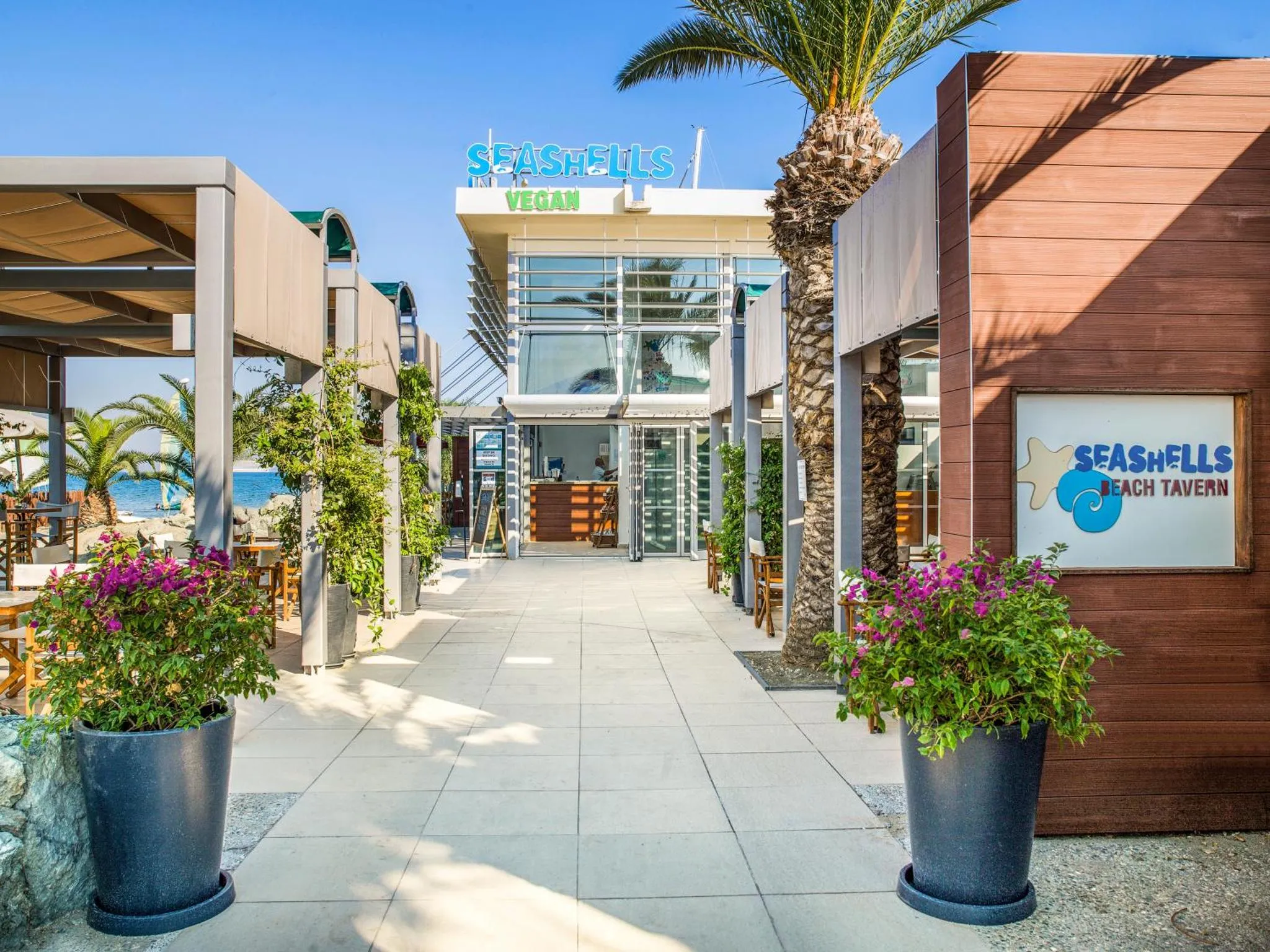 Entree d'un restaurant en bord de mer avec des plantes en pots.