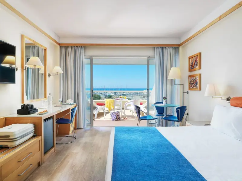 Chambre lumineuse avec vue sur la mer depuis un balcon.