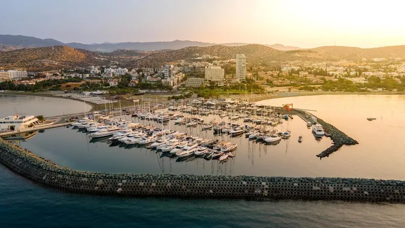 Vue aérienne d'une marina bordée de montagnes au coucher du soleil.