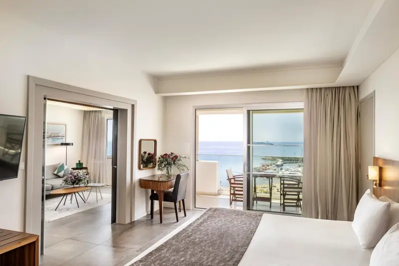 Une chambre lumineuse s'ouvre sur un balcon avec vue sur la mer.