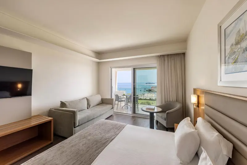 Une chambre lumineuse avec un canapé et un accès à un balcon avec vue sur la mer.