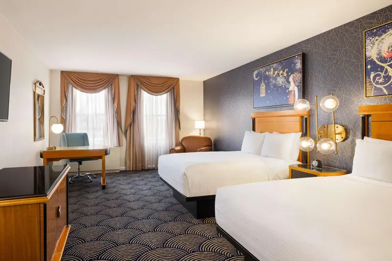Chambre avec deux lits et bureau près d'une fenêtre.