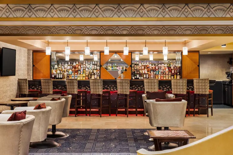 Un bar lumineux avec un comptoir bien garni et des sièges confortables.