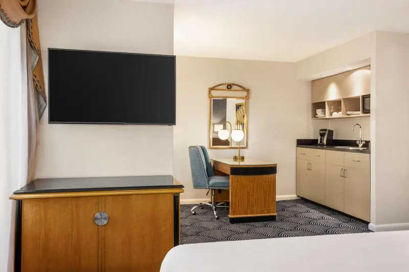 Une chambre d'hôtel avec un bureau et une kitchenette intégrée.