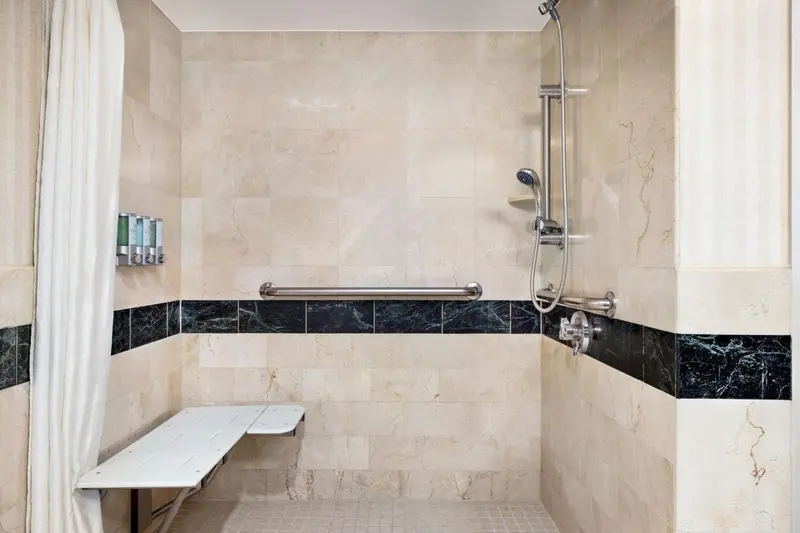 Douche à l'italienne avec pommeau réglable et siège rabattable.