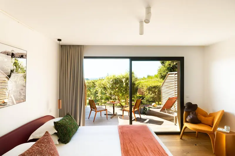 Une chambre lumineuse s'ouvre sur une terrasse avec mobilier de jardin.