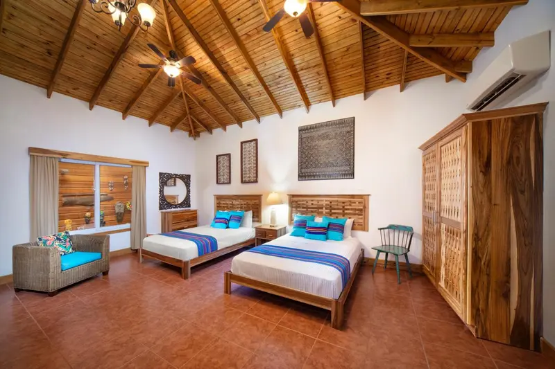 Chambre lumineuse avec deux lits et décoration en bois.