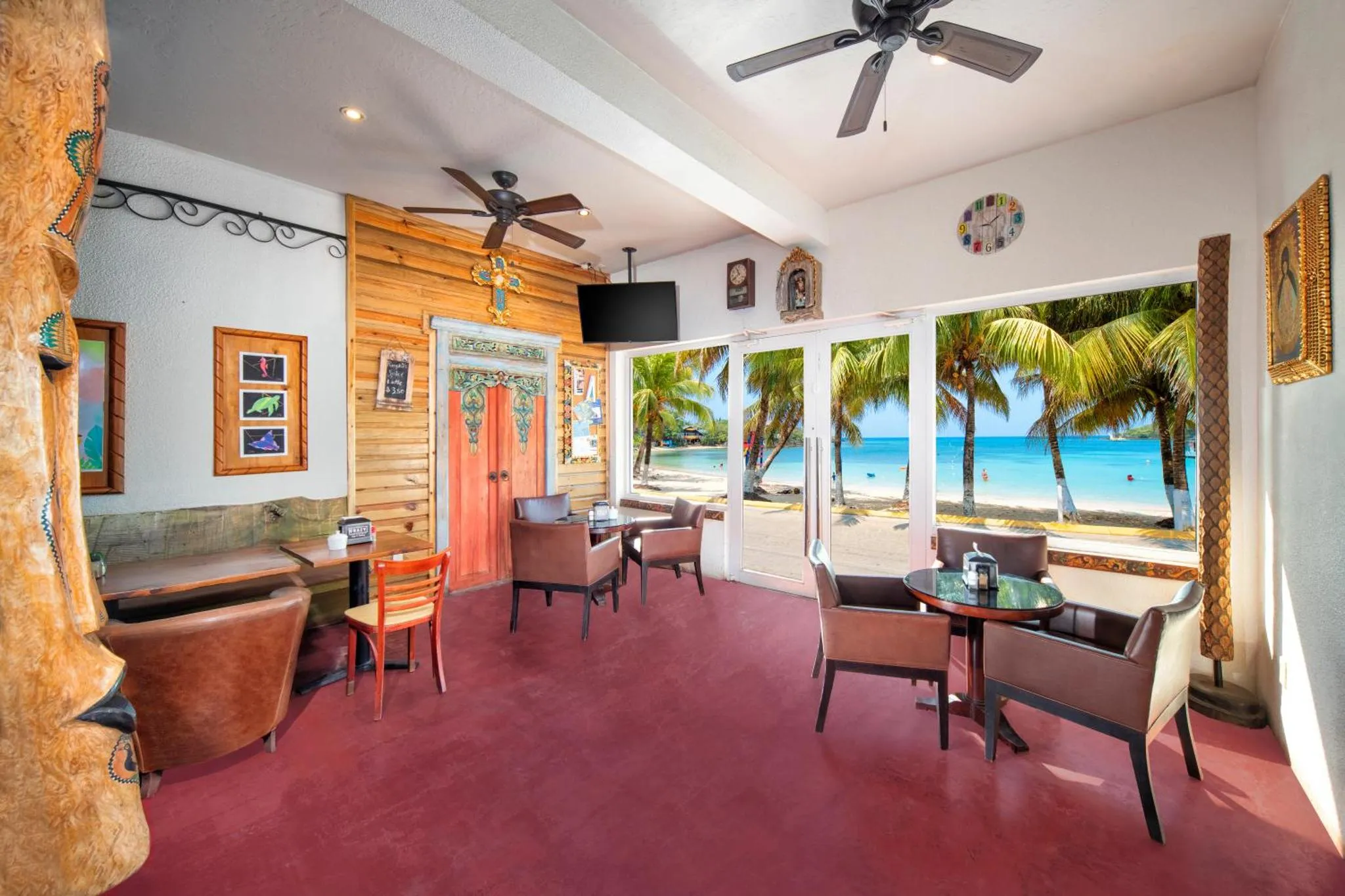 Une salle à manger lumineuse s'ouvre sur une plage de sable blanc et une mer turquoise.