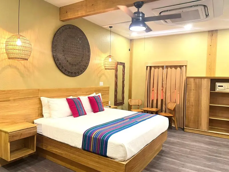 Une chambre lumineuse avec un grand lit recouvert d'une courtepointe colorée.