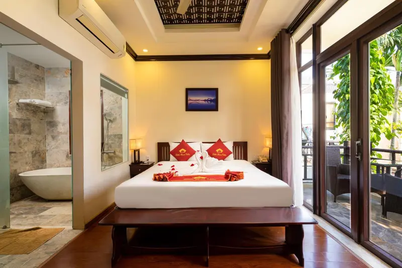 Chambre lumineuse avec un grand lit et une salle de bain ouverte.