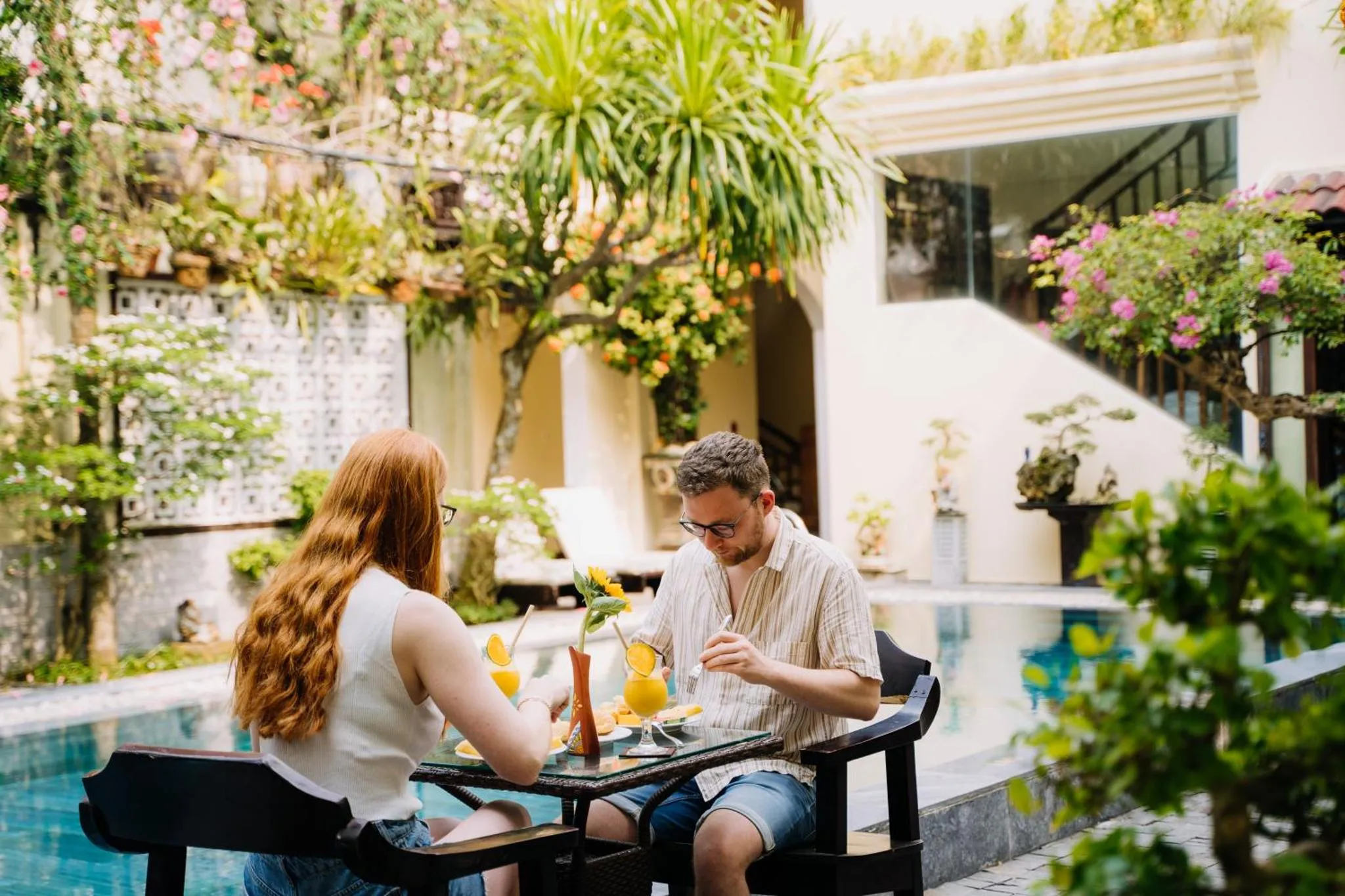 Un couple prend son petit-déjeuner près d'une piscine ensoleillée.