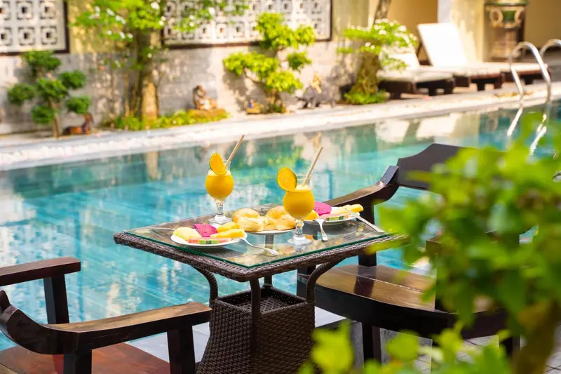 Une table basse avec des boissons et des collations est placée au bord d'une piscine.