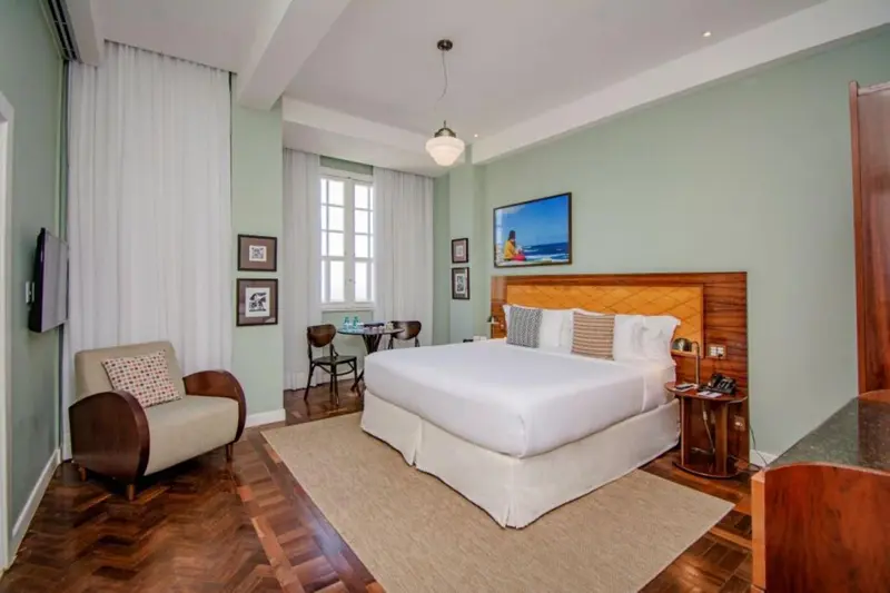 Chambre lumineuse avec un grand lit et un coin salon.