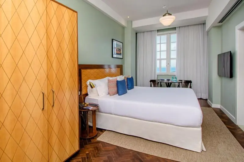 Une chambre lumineuse avec un grand lit et un meuble en bois décoratif.