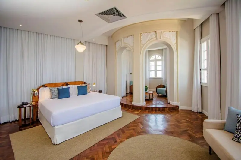 Une chambre lumineuse avec un grand lit et un parquet en bois.