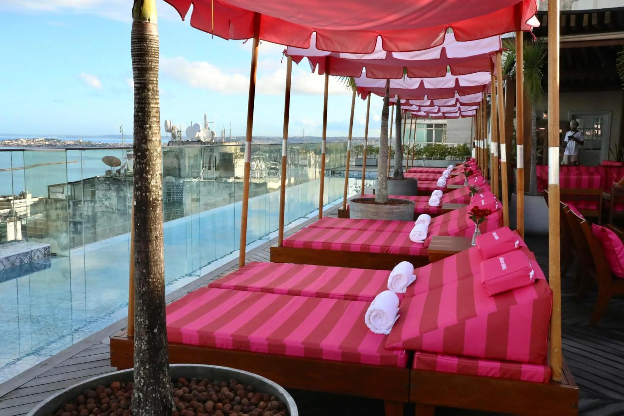 Transats roses et rayés disposés au bord d'une piscine à débordement avec vue sur la mer.