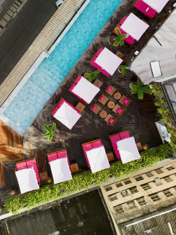 Vue aérienne d'une piscine bordée de transats et de parasols.
