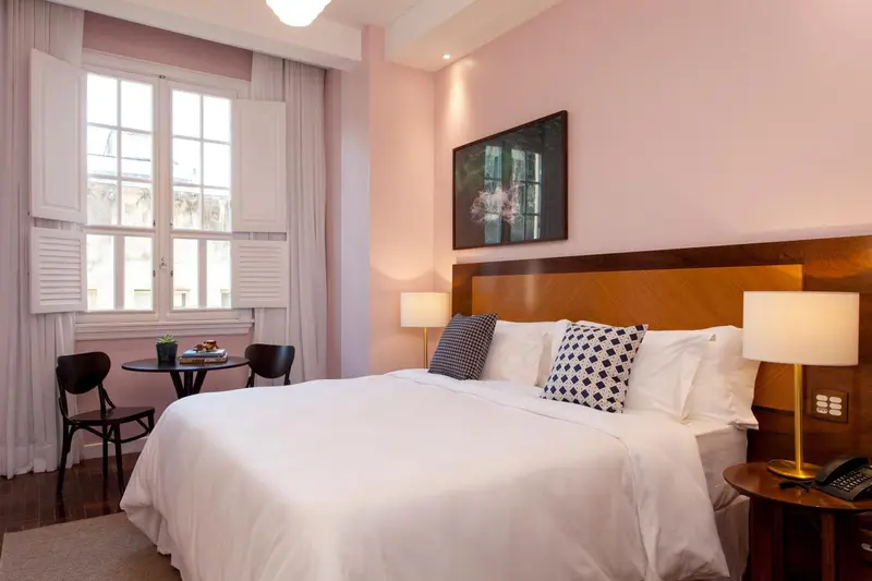 Une chambre lumineuse avec un grand lit et une table basse près de la fenêtre.