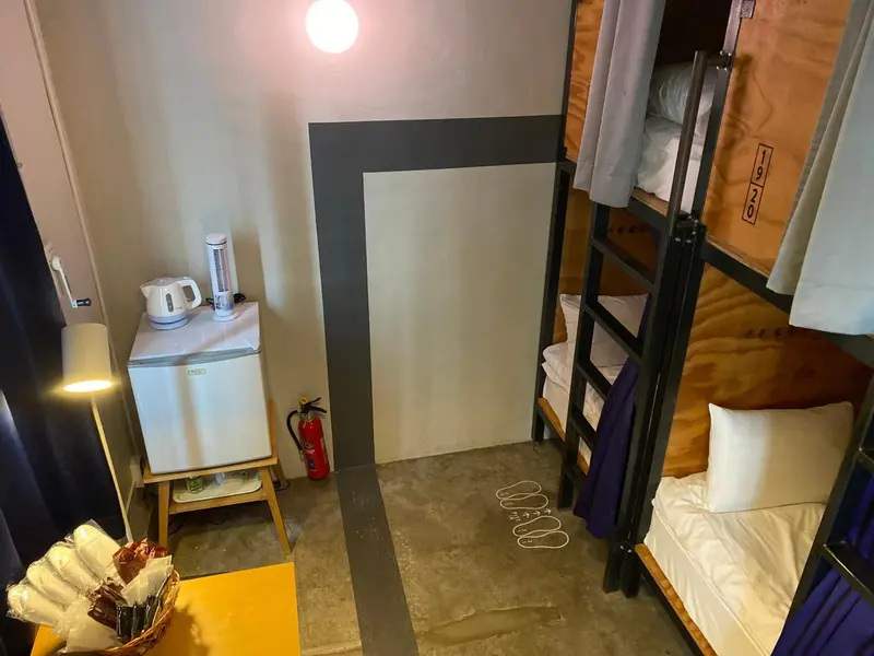 Une chambre avec des lits superposés et un petit réfrigérateur.