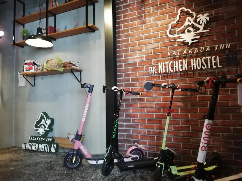 Intérieur d'une pièce avec un mur de briques, des étagères et des trottinettes électriques.