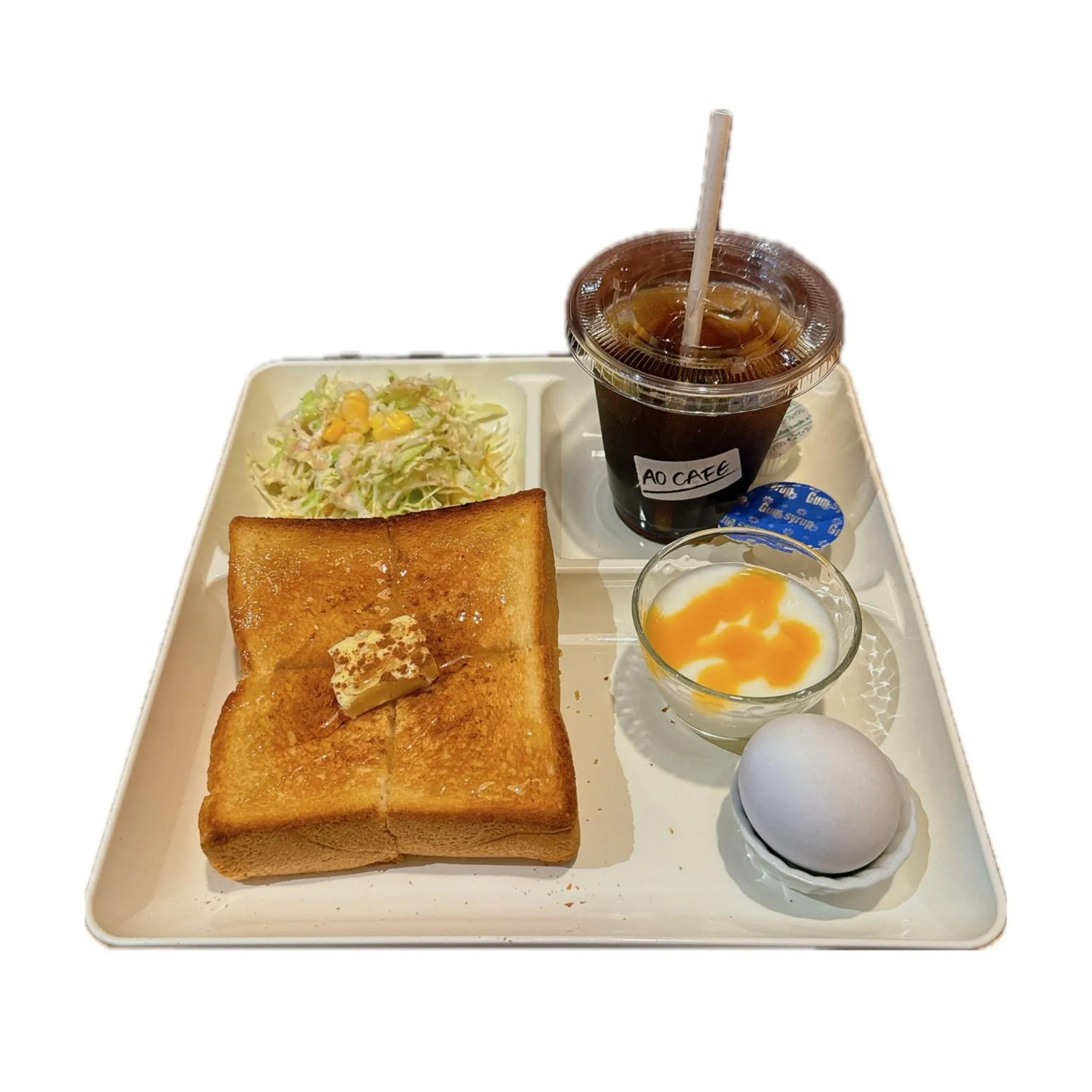 Un plateau repas avec une boisson glacée, une salade, des toasts beurrés et un œuf mollet.