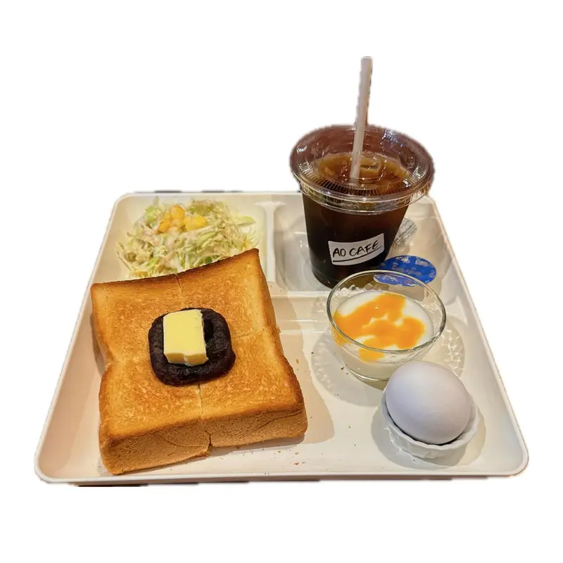 Un plateau repas avec une boisson glacée, une salade, des toasts beurrés et un œuf mollet.