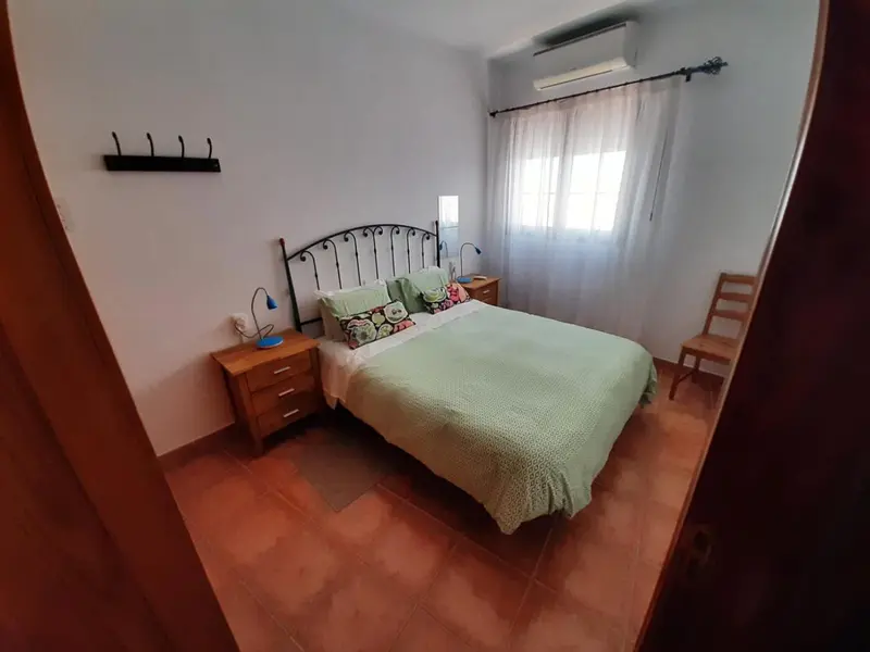 Une chambre avec un lit recouvert d'une courtepointe verte et des oreillers décorés.