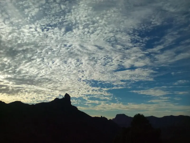 Ciel nuageux au-dessus d'une silhouette de montagne.