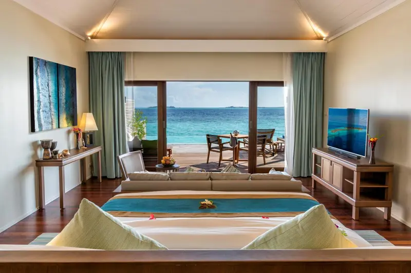 Une chambre lumineuse avec un grand lit donnant sur une terrasse et la mer.