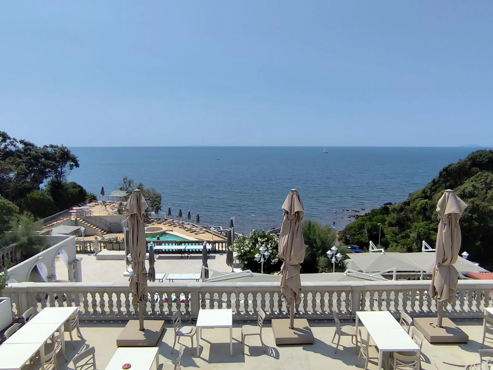 Terrasse avec tables et parasols donnant sur la mer.