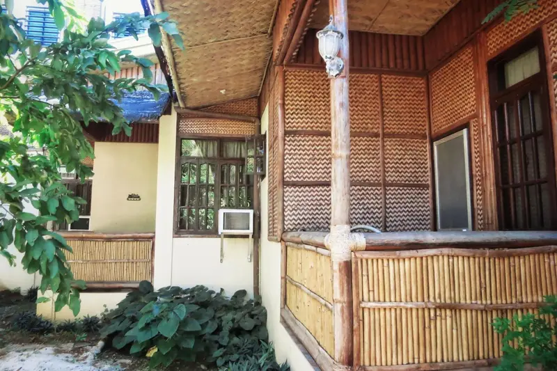 Terrasse ombragée devant une façade en bambou.