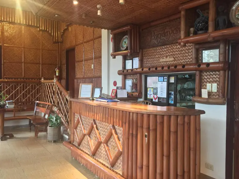 Un comptoir d'accueil en bois tressé dans un hall d'entrée lumineux.