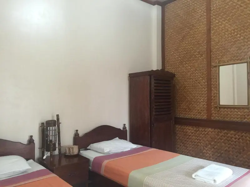 Une chambre avec deux lits simples et un meuble en bois.