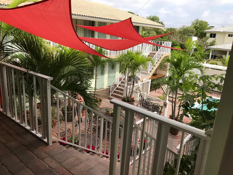 Terrasse ombragée donnant sur une cour intérieure avec piscine et végétation tropicale.