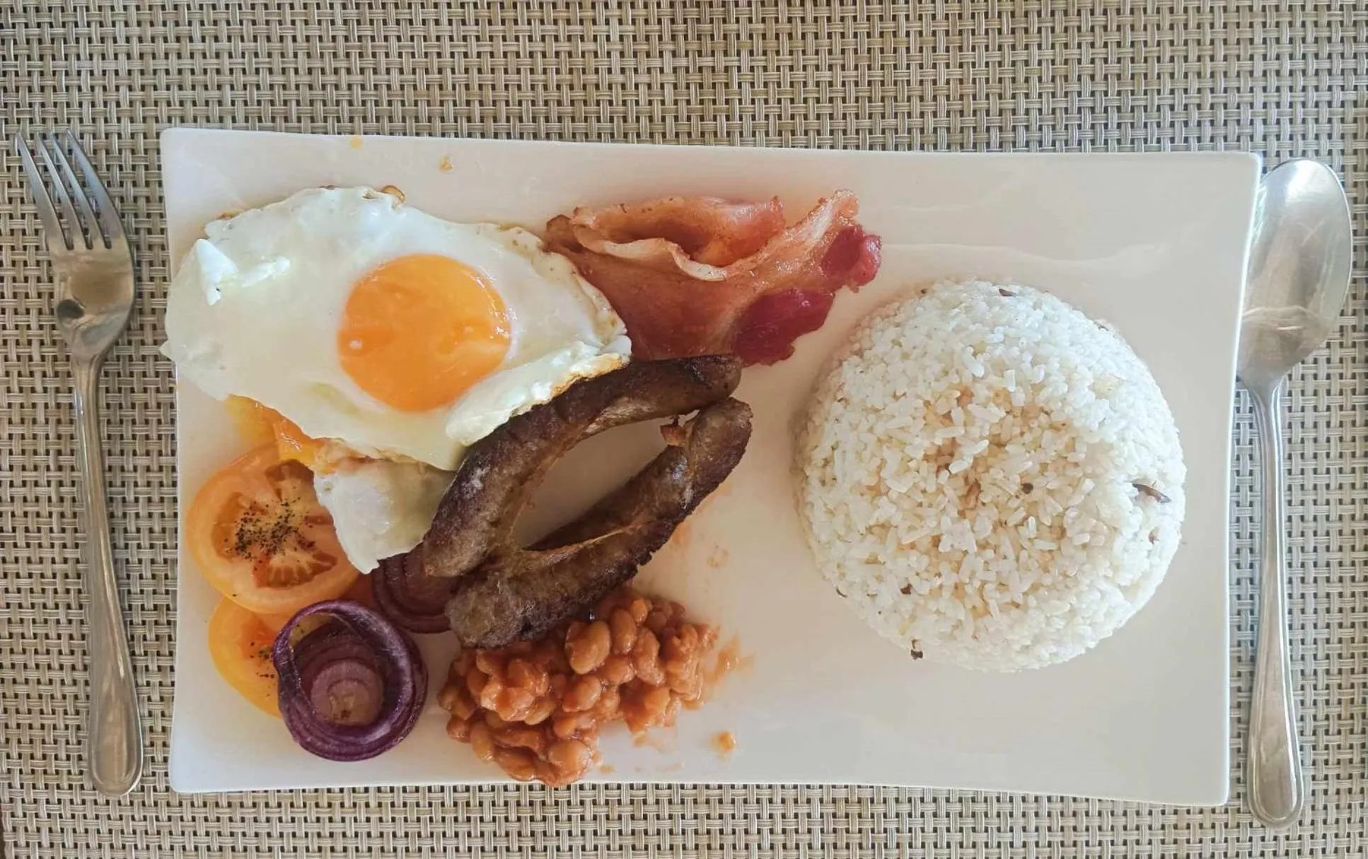 Assiette copieuse avec œufs, bacon, saucisses, haricots et riz.