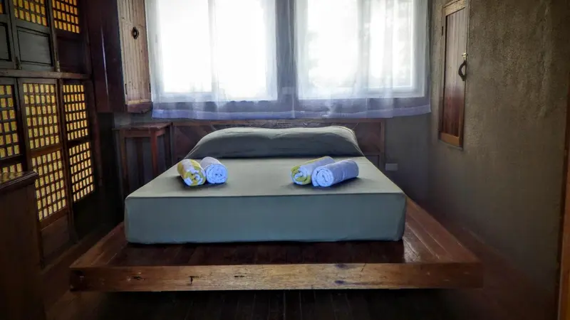Une chambre avec un lit simple décoré de serviettes roulées.