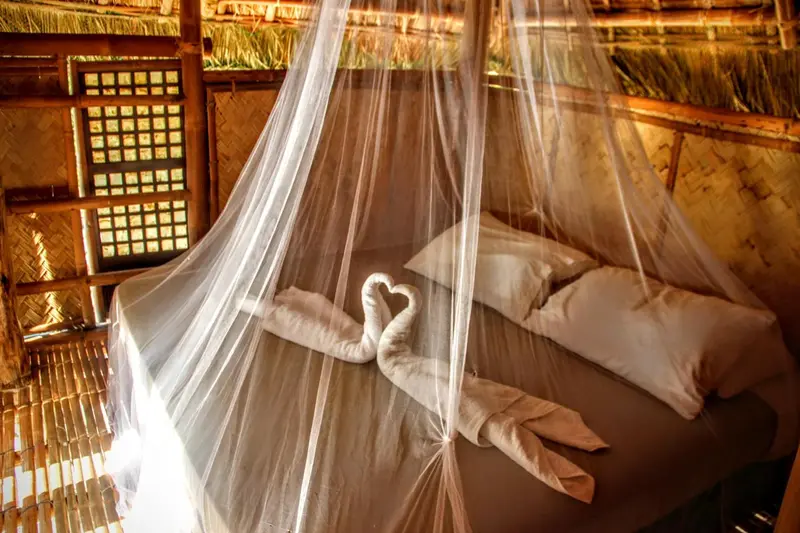 Lit préparé avec des serviettes en forme de cœur dans une chambre rustique.