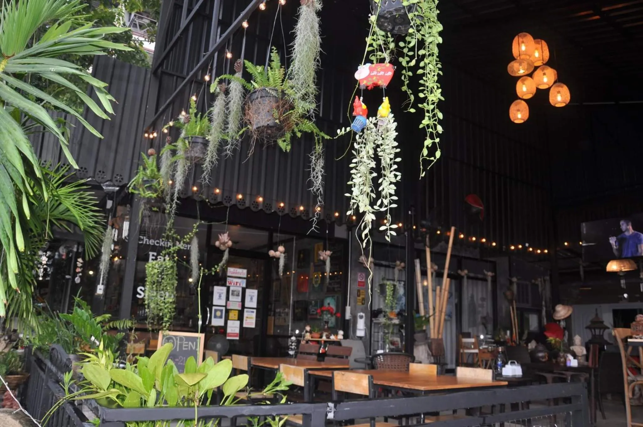Terrasse ombragée avec tables et végétation suspendue.