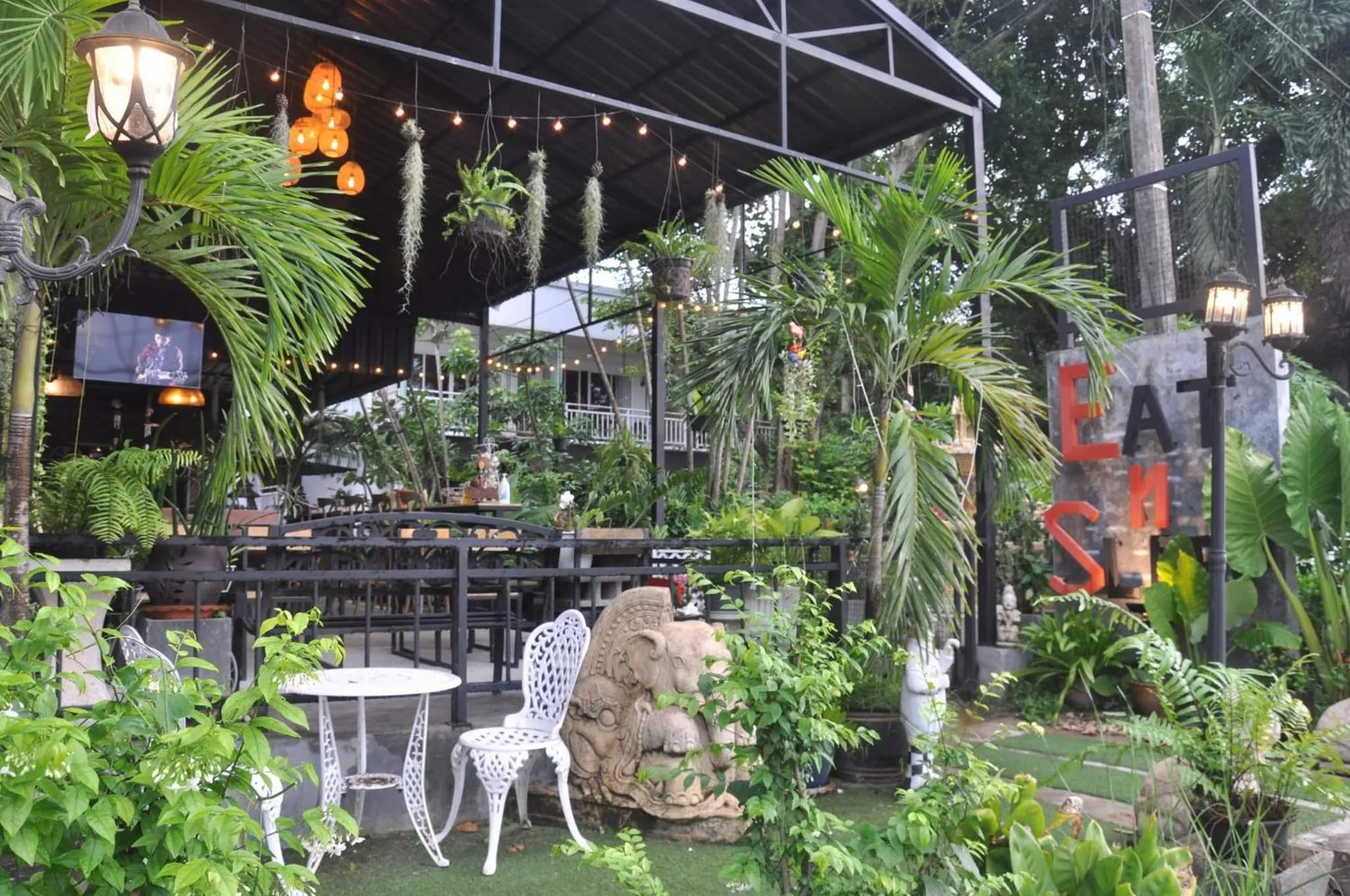 Terrasse ombragée avec tables et chaises au milieu d'une végétation luxuriante.