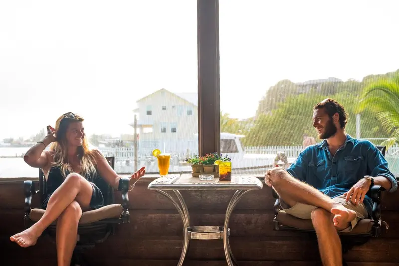 Un couple est assis à une table ensoleillée près d'une fenêtre.