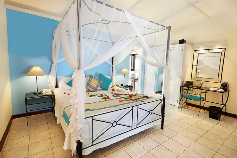 Une chambre lumineuse avec un lit à baldaquin décoré de moustiquaire et de fleurs.