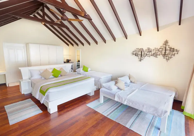 Chambre lumineuse avec deux lits simples et un coin salon.