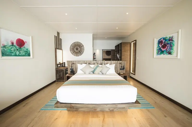 Une chambre lumineuse avec un grand lit et des œuvres d'art murales.